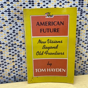 May include: A yellow and orange book titled "The American Future: New Visions Beyond Old Frontiers by Tom Hayden".