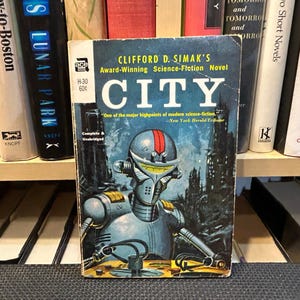 May include: A vintage science fiction novel titled "CITY" by Clifford D. Simak. The cover features a robot with a red stripe on its head, set against a futuristic cityscape. The book is part of a collection.