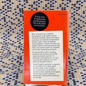 May include: A red paperback book with the title "Psychology" and the text "If you want to understand psychoanalysis this is the book you read first." on the cover. The back cover features a description of the book and its author, Sigmund Freud.