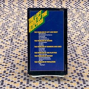 May include: A book cover with a yellow and blue design. The title is "The Left Hand of the Electron". The book explores scientific concepts like the asymmetry of life, the nature of oceans, and the properties of numbers and lines.