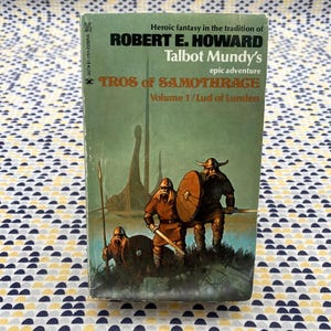 May include: A green paperback book cover with the title "Tros of Samothrage" by Talbot Mundy. The book is an epic adventure in the tradition of Robert E. Howard. The cover features an illustration of three warriors in a fantasy setting.
