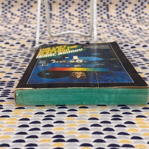 May include: A paperback book titled "The Left Hand of the Galaxy" by Isaac Asimov. The cover features a blue and black background with a colorful spectrum and a small image of a man in a white shirt.