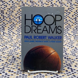 May include: A paperback book titled "HOOP DREAMS" by Paul Robert Walker. The book is a young adult adaptation based on the film by Steve James, Frederick Marx, & Peter Gilbert. The cover features a basketball.