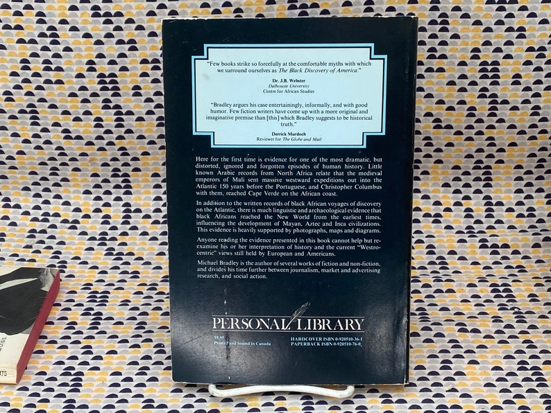May include: The back cover of a paperback book titled "The Black Discovery of America" by Michael Bradley. The cover is dark with white text and includes quotes and a summary of the book's content. The book is from Personal Library.