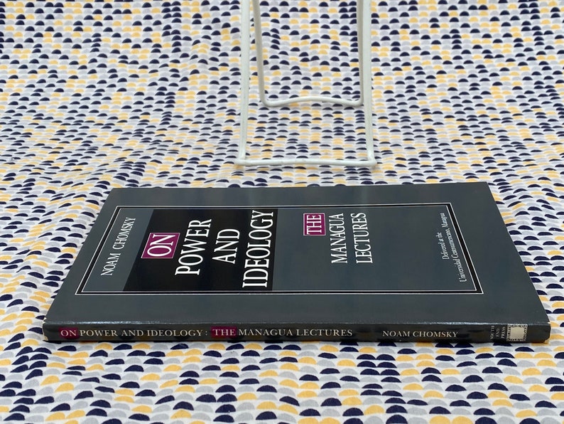 Op de afbeelding: Een zwart hardback boek getiteld "On Power and Ideology: The Managua Lectures" door Noam Chomsky. De boekomslag heeft witte tekst en een witte rand.