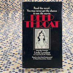 May include: A vintage paperback book titled "DEEP THROAT" with a black cover and red lettering. The cover features an illustration of a woman and text that reads "Meet the Amazing Linda Lovelace".