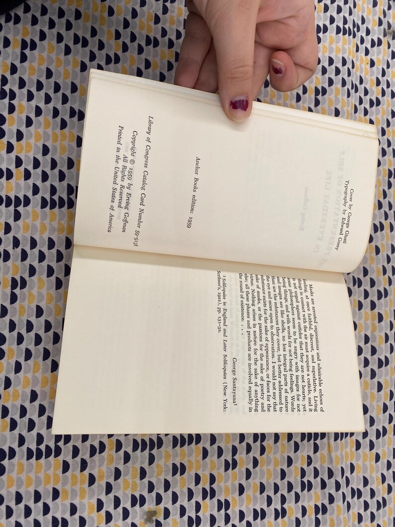 Puede incluir: Un libro abierto con texto, sostenido por una persona. Las p&aacute;ginas del libro son de color blanquecino, con texto negro. La portada no es visible. El libro es una edici&oacute;n de Anchor Books de 1959, con un n&uacute;mero de tarjeta de cat&aacute;logo de la Biblioteca del Congreso.