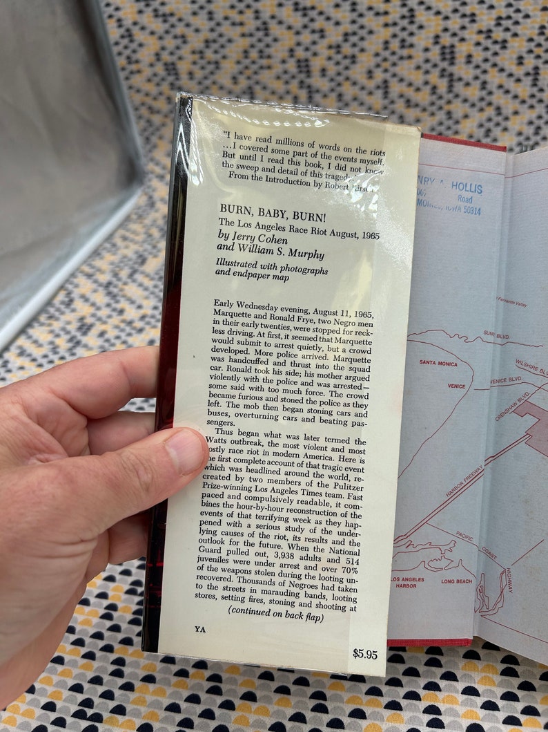 May include: A book cover with a black and white photo of a burning car and a title that reads "Burn, Baby, Burn! The Los Angeles Race Riot August, 1965" by Jerry Cohen and William S. Murphy. The book cover also includes a map of Los Angeles.