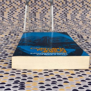 May include: A book titled "Corporate Power in America" edited by Ralph Nader and Mark J. Green. The cover features a blue and black image of a city skyline.