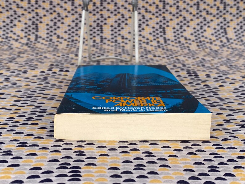 May include: A book titled "Corporate Power in America" edited by Ralph Nader and Mark J. Green. The cover features a blue and black image of a city skyline.