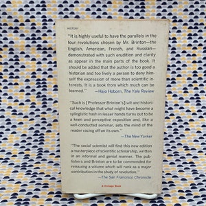 Puede incluir: Una cubierta de libro con fondo blanco y texto negro. El texto incluye citas de rese&ntilde;as del libro, incluyendo los nombres de los cr&iacute;ticos y las publicaciones de las que provienen. El libro trata sobre la historia de las revoluciones.