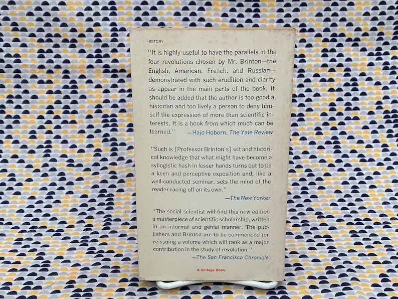 Puede incluir: Una cubierta de libro con fondo blanco y texto negro. El texto incluye citas de rese&ntilde;as del libro, incluyendo los nombres de los cr&iacute;ticos y las publicaciones de las que provienen. El libro trata sobre la historia de las revoluciones.