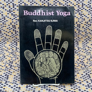 May include: A black book with the title "Buddhist Yoga" and the author "Rev. KANJitsu IIJIMA" in white text. The cover features a black and white illustration of a hand with a circle in the palm.