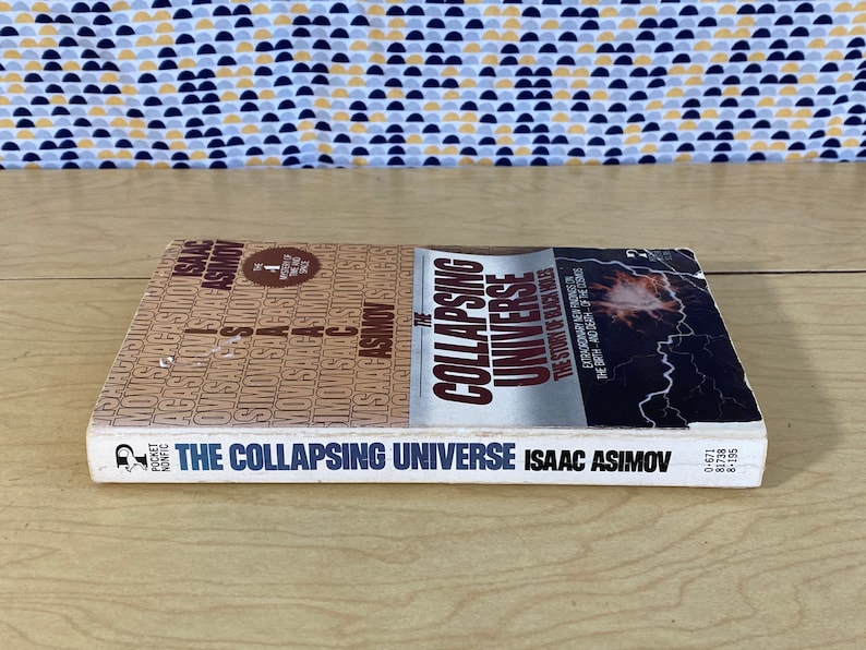 May include: A white paperback book titled "The Collapsing Universe" by Isaac Asimov. The cover features a red and white graphic of a collapsing star with a black background.