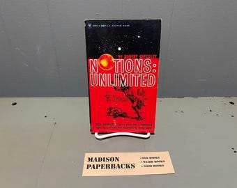 Könnte beinhalten: Ein Vintage-Taschenbuch mit dem Titel Notions: Unlimited von Robert Sheckley mit einem schwarz-roten Einband, der eine grafische Abbildung einer Figur und einer orangefarbenen Sonne zeigt, auf einem weißen Ständer.