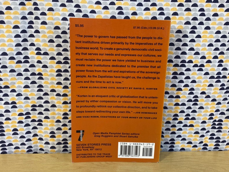 May include: The back cover of a book titled "Globalizing Civil Society" by David C. Korten. The cover is orange with black text and a barcode. The book is published by Seven Stories Press and distributed by Publishers Group West.
