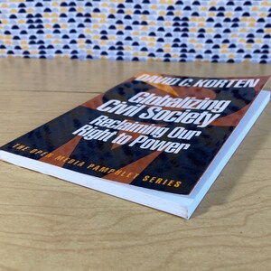 May include: A paperback book titled "Globalizing Civil Society: Reclaiming Our Right to Power" by David C. Korten. The book cover features a black and orange design with the title in white text.