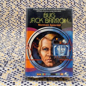 May include: A book cover with a blue, orange, and white design. The title is "Bug Jack Barron" by Norman Spinrad. The cover features a man's face with a television screen showing a woman's face.