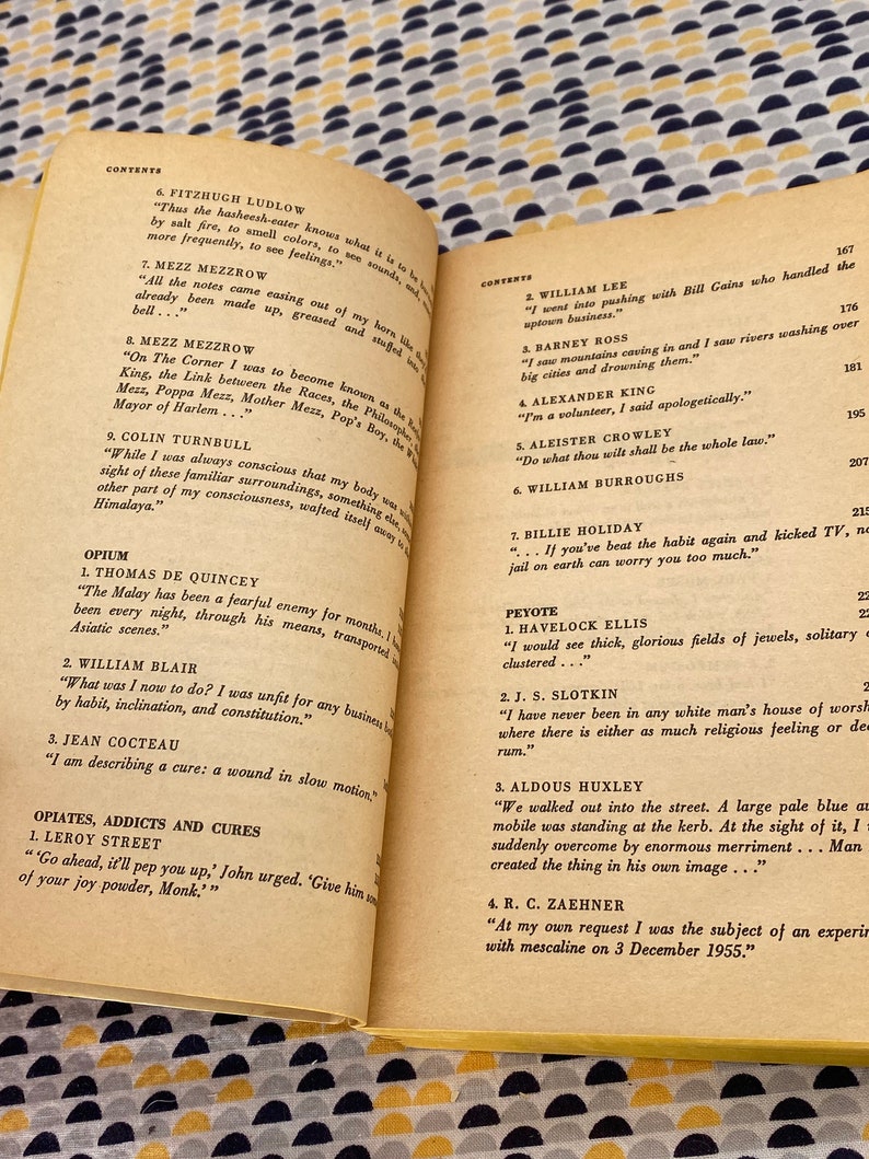 May include: A close-up of a book with a white cover and black text. The book is open to a page with a list of contents, including names like Fitzhugh Ludlow, Mezz Mezzrow, and William Lee. The book appears to be a collection of writings about various topics.