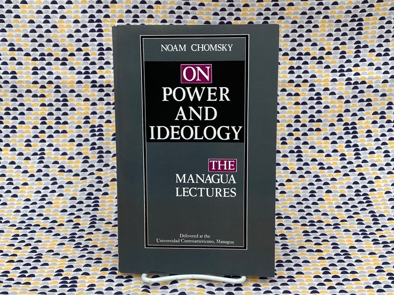 Op de afbeelding: Een grijs boek met de titel "On Power and Ideology: The Managua Lectures" van Noam Chomsky. De omslag van het boek heeft witte tekst op een grijze achtergrond.
