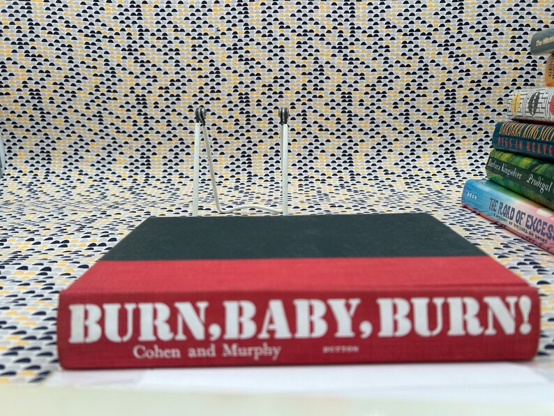May include: A red hardcover book with the title "BURN, BABY, BURN!" in white letters. The author's names, "Cohen and Murphy", are printed in white below the title.