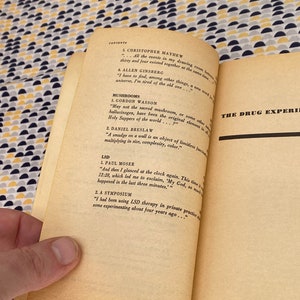 May include: A close-up of a book page with the title "The Drug Experience" and a list of contents including "Mushrooms", "LSD", and "A Symposium".