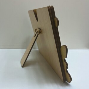 May include: A wooden picture frame with a stand on the back. The frame is made of light wood and has a natural finish.