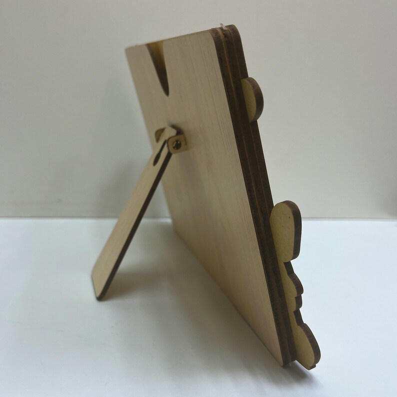 May include: A wooden picture frame with a stand on the back. The frame is made of light wood and has a natural finish.