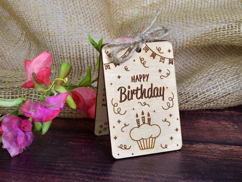 Finished engraved wood card with a cupcake design and "Happy Birthday" text. Hand-assembled wooden greeting card tied with twine, perfect as a bday gift for a friend. Compatible with CO2 laser machines.