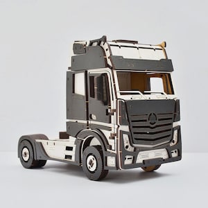 May include: A white and black wooden model of a semi-truck with a detailed cab and a flatbed trailer.