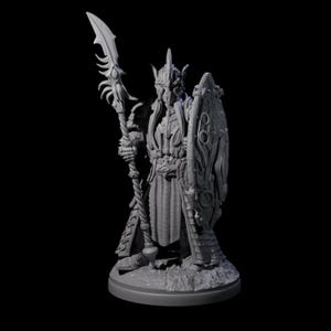 May include: A gray, detailed figurine of a warrior in ornate armor, holding a spear and shield. The warrior has a helmet with horns and a long, flowing cape. The shield features a decorative design. The figurine is on a round base.