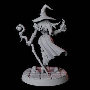May include: A gray 3D printed miniature of a female witch wearing a pointed hat and holding a staff with a sphere on top. She is wearing a long robe and has long hair. She is standing on a circular base with a stone texture.