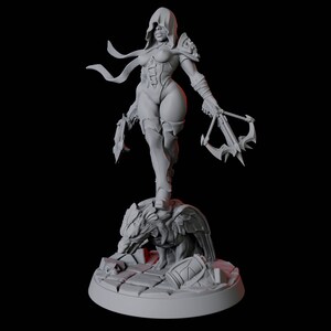 May include: A gray figurine of a female warrior in a hooded cloak, holding a crossbow and a blade. She stands atop a detailed sculpture of a creature, with a shield and other elements at the base. The figure is set against a dark background.