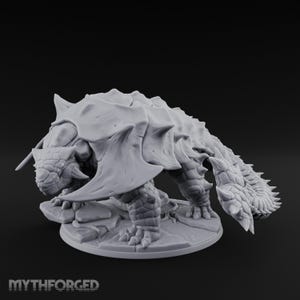 May include: A light grey, unpainted resin miniature of an ankylosaurus-like creature with a heavily armoured, spiked shell, a clubbed tail, and textured skin, standing on a circular stone-tiled base with the text MYTHFORGED printed at the bottom.