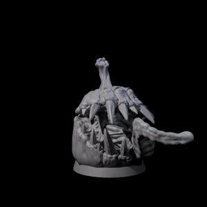 May include: A gray, 3D-printed model of a creature's head with sharp teeth and a long, finger-like appendage. The model has a rough texture and is set against a black background. The creature's mouth is open, revealing multiple sharp teeth.