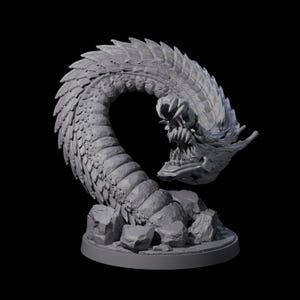 May include: A grey sculpture of a worm-like creature with a large, toothed mouth. The creature is coiled, with a segmented body and a spiky back. It rests on a base with rock formations.