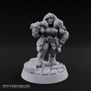 May include: A gray miniature figurine of a female warrior, holding a hammer. She is wearing armor and standing on a stone base. The figurine has long hair and is smiling. The base has the text "MythForged".