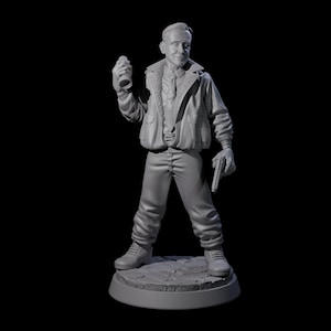 May include: A grey figurine of a man in a bomber jacket, trousers, and boots, holding a bottle and a gun. The figure stands on a circular base with a cobblestone design, against a black background.