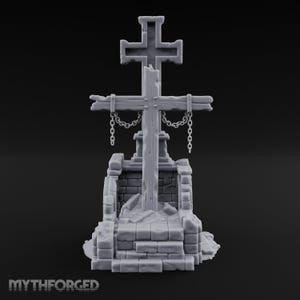 May include: A gray, unpainted miniature model of a weathered wooden cross standing atop a stone-like base. The cross features a smaller crossbar with hanging metal-style chains. The base is constructed from stacked, textured stone blocks.