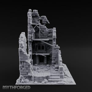 Puede incluir: Una figura en miniatura gris sin pintar de una torre de piedra en ruinas con ladrillos visibles, andamios de madera internos y escombros en el suelo. La estructura presenta puertas arqueadas y paredes rotas. El texto MYTHFORGED está en la parte inferior.