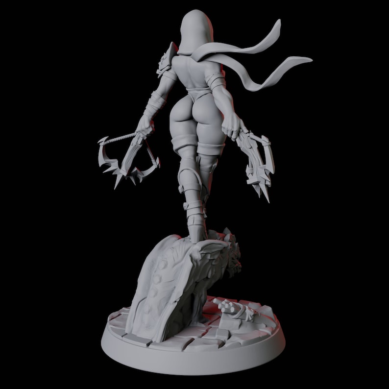 May include: A gray figurine of a female warrior, viewed from the back, holding two crossbows. She wears a hooded cowl, shoulder armor, and form-fitting clothing. The figure stands on a rocky base with a circular platform.