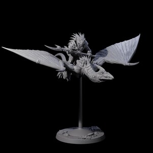 May include: A grey miniature figurine of a fantasy creature riding a dragon. The rider holds a spear, and the dragon has large wings. The figurine is mounted on a stand with a circular base, set against a black background.