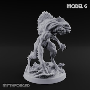 Puede incluir: Figura gris detallada de una criatura con cabeza con aletas, dientes afilados y manos y pies con garras. La figura está sobre una base texturizada. Los textos "MODEL G" y "MYTHFORGED" son visibles.