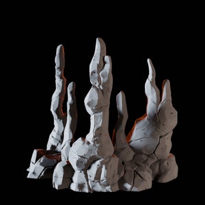 May include: A white, sculpted rock formation resembling a cluster of tall, thin spires. The rock is textured and appears to be made of plaster or clay.