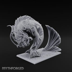 Peut inclure: Une figurine en résine grise représentant une créature hybride mythique entre dragon et poisson, avec des écailles détaillées, des nageoires fluides et une fleur sur la tête. Elle repose sur un socle rectangulaire avec un petit pont.