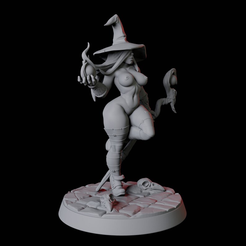 May include: A gray, detailed miniature figurine of a female witch wearing a pointed hat and holding a staff with a glowing orb. The witch is standing on a circular base with a cobblestone design.