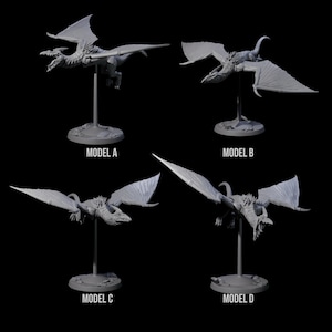 May include: Four grey dragon models in different flying poses, each mounted on a stand. The models are labelled A, B, C, and D. The dragons have detailed wings, open mouths, and textured bodies, set against a black background.