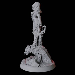 May include: A gray figurine of a hooded figure holding a crossbow, standing on a detailed dragon-like creature. The figure is wearing armor and boots. The base is round and has a stone-like texture.