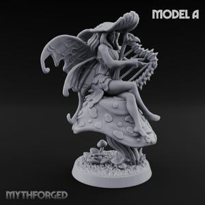 May include: A grey figurine of a fairy playing a harp, seated on a mushroom. The fairy has large, detailed wings and is wearing a leaf-like outfit. The base of the figurine features small mushrooms and grass. The text "MODEL A" is visible.