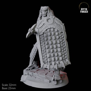 May include: A gray, 3D-printed miniature of a fantasy warrior with a shield. The warrior has a detailed, textured design, including a scaled shield and armor. The base is 25mm, and the figure is 32mm tall. The Myth Forged logo is in the upper right.
